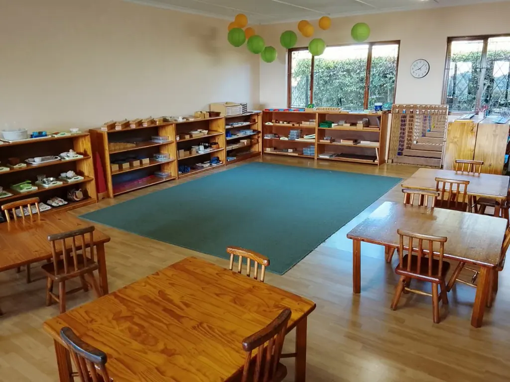 A Montessori classroom with materials on open shelving around a large green rug
