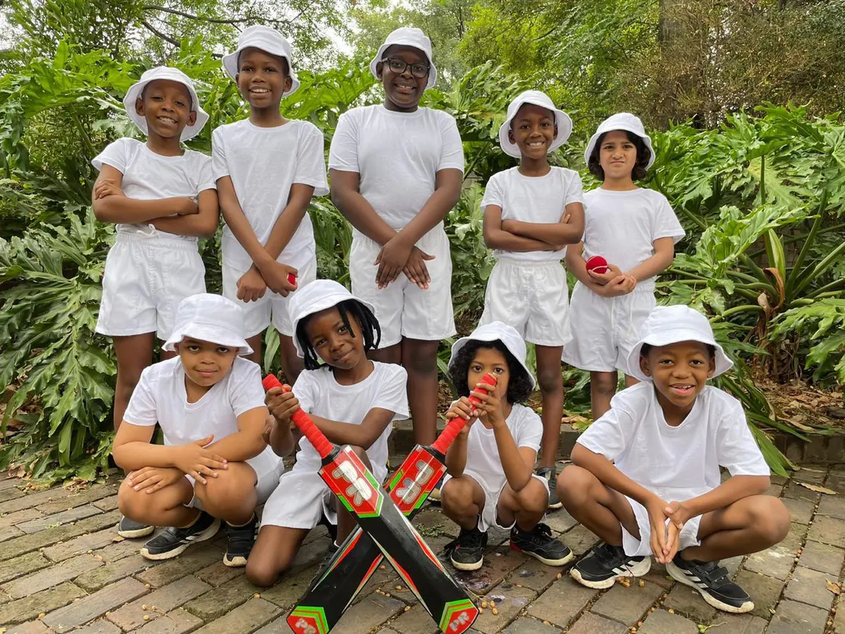A group of primary school children in white sports kit on the school grounds