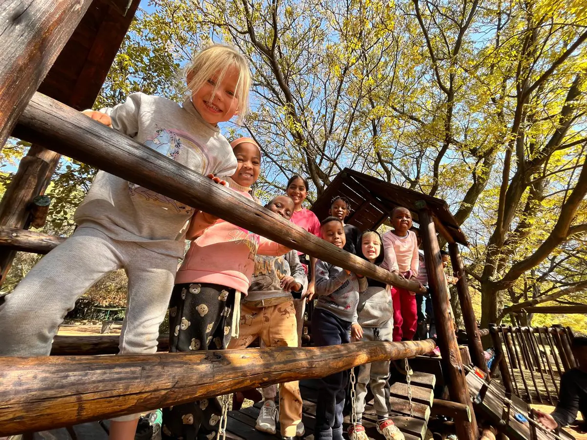 Children playing on a wooden climbing structure in the school grounds